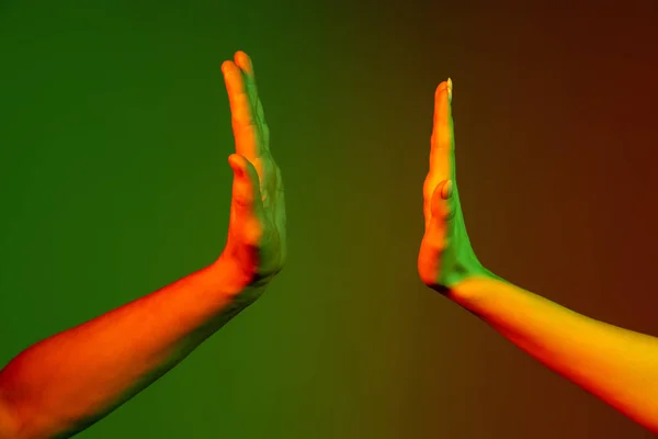 Zwei menschliche Hände gestikulieren isoliert auf grünem Studiohintergrund im Neonlicht. Konzept menschlicher Beziehung, Gemeinschaft, Zusammengehörigkeit — Stockfoto