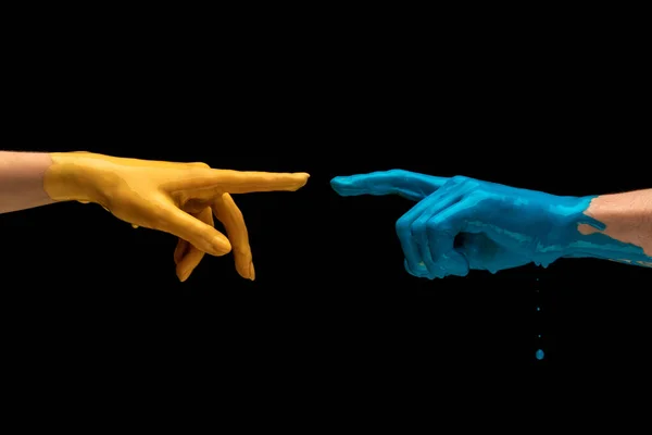 Blauw en geel geschilderde handen proberen elkaar te raken geïsoleerd op donkere achtergrond. Begrip menselijke relatie, gemeenschap, saamhorigheid, symboliek, cultuur en geschiedenis — Stockfoto