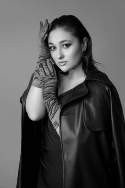 Gri stüdyo arka planında izole edilmiş güzel bir kadının yarım boy monokrom portresi. Güzellik, moda, tarz, vücut pozitifliği