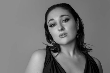 Gri stüdyo arka planında izole edilmiş güzel bir kadının monokrom portresi. Güzellik, moda, tarz, vücut pozitifliği