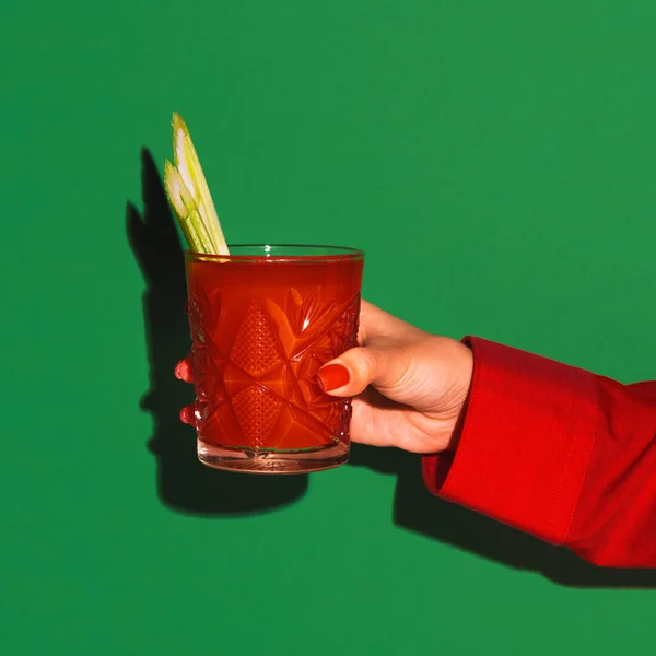 Mão feminina segurando vidro com coquetel sangrento mary isolado em fundo de néon verde brilhante. Conceito de gosto, bebidas alcoólicas — Fotografia de Stock