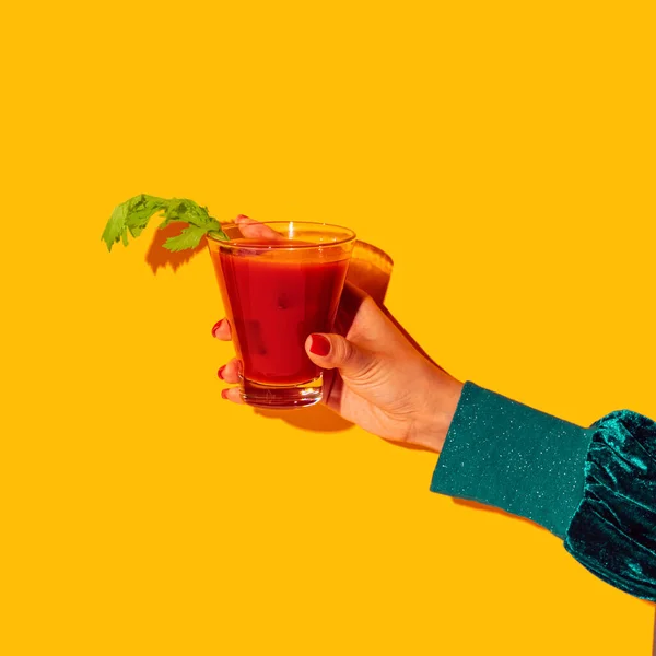 女性的手与血腥的玛丽玻璃隔离在明亮的黄色霓虹灯背景。品味的概念，酒精饮料 — 图库照片