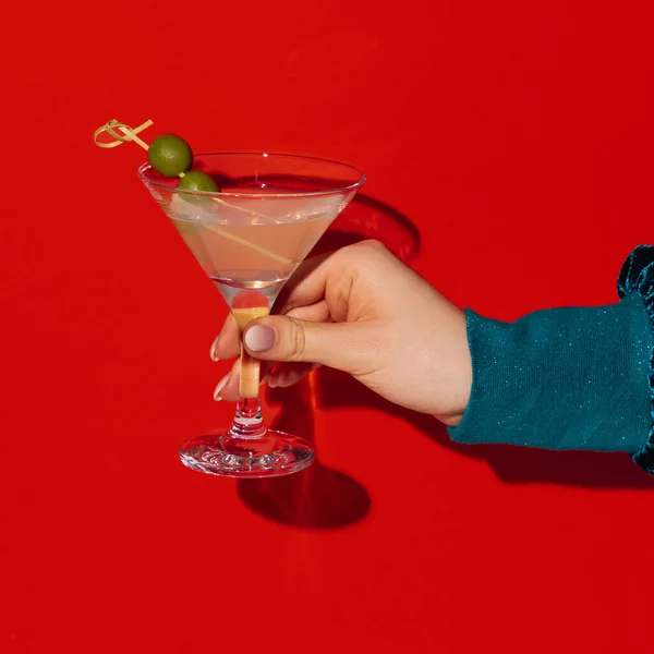 女性的手捧着马提尼玻璃杯，橄榄与明亮的红色霓虹灯背景隔离，阴影。品味的概念，酒精饮料 — 图库照片