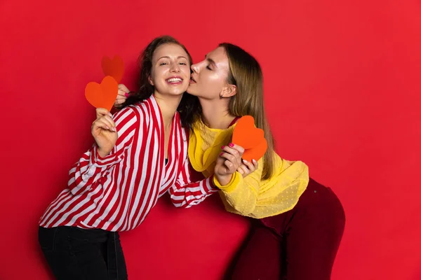 Retrato de duas jovens meninas felizes isoladas em fundo vermelho. Celebração do dia dos namorados. Conceito de emoções, amor, relações, férias românticas. — Fotografia de Stock
