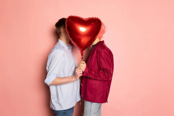 Pareja joven sosteniendo globos en forma de corazones. Celebración de San Valentín. Concepto de emociones, expresión facial, amor, relaciones, vacaciones románticas. —  Fotos de Stock