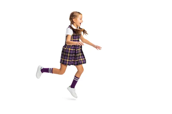 Retrato de menina bonito, aluno em uniforme escolar correndo isolado no fundo branco. Conceito de infância, emoções, estudo — Fotografia de Stock