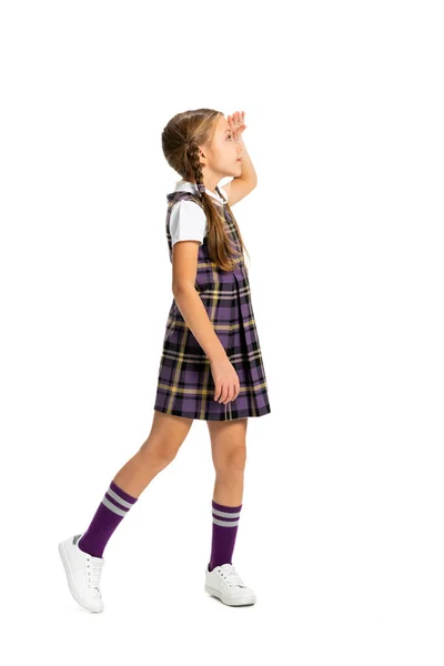 Visão de perfil da criança, menina, aluno de uniforme escolar em pé isolado sobre fundo branco. Conceito de infância, emoções, estudo — Fotografia de Stock