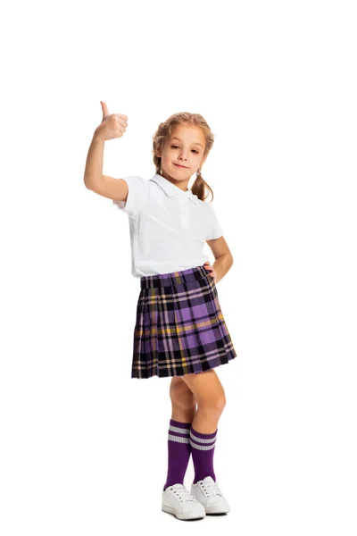 Весела дитина, маленька дівчинка, учень у шкільній формі позує ізольовано на білому тлі. Концепція дитинства, емоцій, навчання — стокове фото