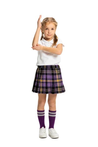 Portrait of cute child, little girl, pupil in school uniform posing isolated on white background. Concept of childhood, emotions, study — Stock Photo, Image