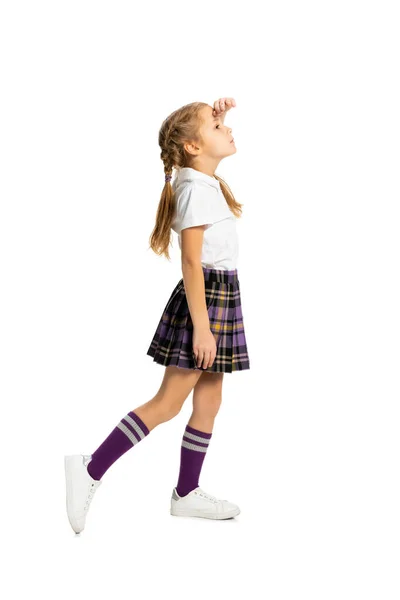 Вид профілю дитини, маленька дівчинка, учень у шкільній формі, що стоїть ізольовано на білому тлі. Концепція дитинства, емоцій, навчання — стокове фото