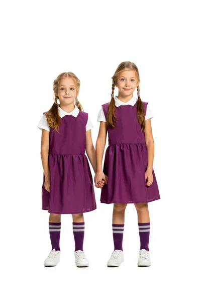 Веселі маленькі дівчата, сестри або брати і сестри носять повсякденний одяг, що стоїть ізольовано на білому фоні студії. Концепція дитинства, емоцій, навчання — стокове фото