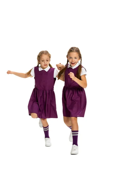 Meninas, irmãs ou irmãos alegres vestindo roupas de estilo casual correndo isolados no fundo do estúdio branco. Conceito de infância, emoções, estudo — Fotografia de Stock