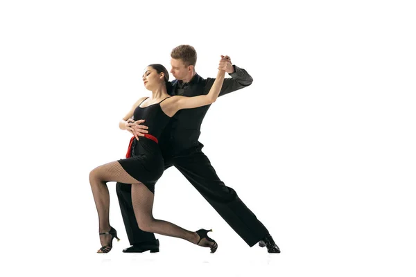 Beautiful sportive young man and woman dancing Argentine tango isolated on white studio background. Artists in black stage costumes — Stock Photo, Image