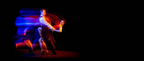 Flyer with two young ballroom dancers dancing Argentine tango isolated on dark background with neon mixed light. — Stock Photo, Image