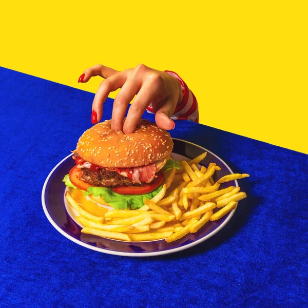 Food Pop Art Fotografie. Weibliche Hand und Hamburger, Pommes frites auf hellblauer Tischdecke auf gelbem Hintergrund. Vintage, Retro-Stil — Stockfoto