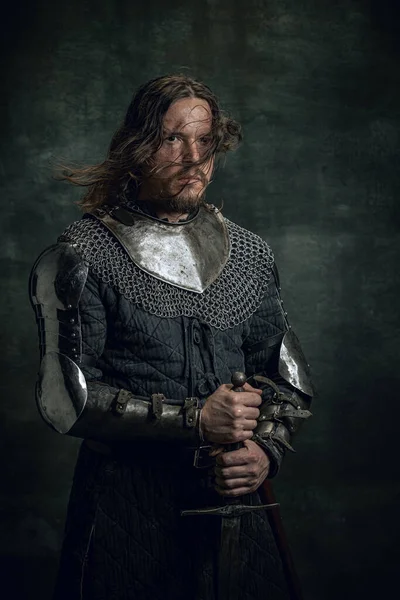 暗い背景に孤立した大きな剣を保持汚れた負傷した顔を持つ中世の戦士や騎士の肖像画。時代、歴史の比較 — ストック写真