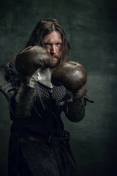 Portrét středověkého válečníka nebo rytíře se špinavou zraněnou tváří boxerské rukavice izolované na tmavém pozadí. Porovnání období, historie — Stock fotografie