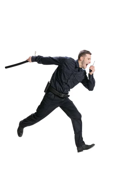 Retrato dinâmico de homem jovem, policial vestindo uniforme preto correndo isolado em fundo branco. Conceito de trabalho, cuidado, lei e ordem. — Fotografia de Stock