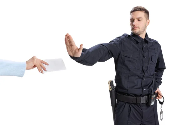 Retrato de homem jovem, policial vestindo uniforme preto recusa um suborno isolado em fundo branco. Conceito de trabalho, cuidado, lei e ordem. — Fotografia de Stock