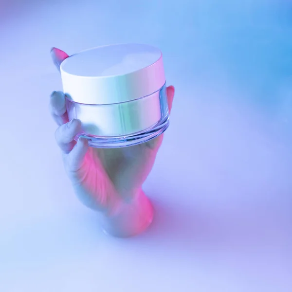 Close up mão feminina segurando frasco cosmético aparece a partir de banho de leite com brilho branco macio em luz de néon. Beaty, cosméticos, moda, arte — Fotografia de Stock