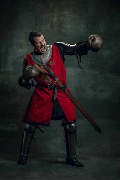 Πορτρέτο του μεσαιωνικού πολεμιστή ή ιππότη με βρώμικο πληγωμένο πρόσωπο σε γάντια πυγμαχίας απομονώνονται σε σκούρο φόντο. Σύγκριση εποχών, ιστορία — Φωτογραφία Αρχείου