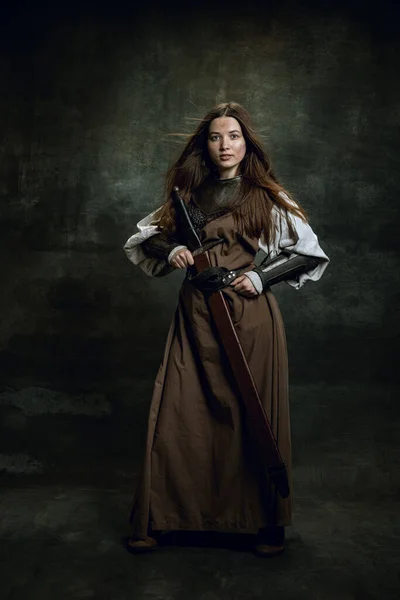 Teljes hosszúságú portré sorozat gyönyörű nő képére középkori harcos vagy lovag piszkos sebesült arc nagy kard elszigetelt sötét vintage háttér. — Stock Fotó