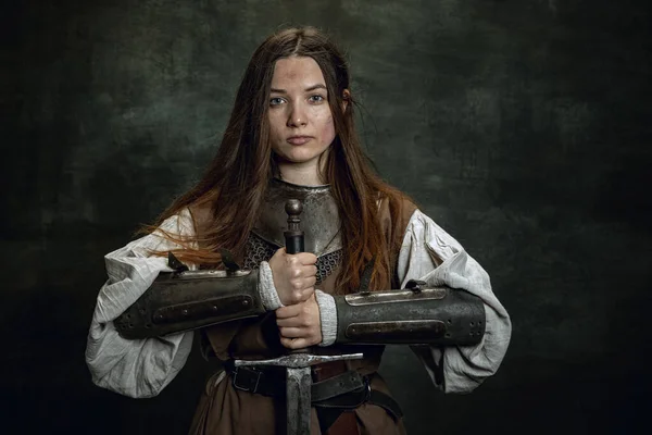 Retrato vintage de mulher adorável, guerreira medieval ou cavaleiro com rosto sujo ferido olhando para a câmera isolada sobre fundo retro escuro. — Fotografia de Stock