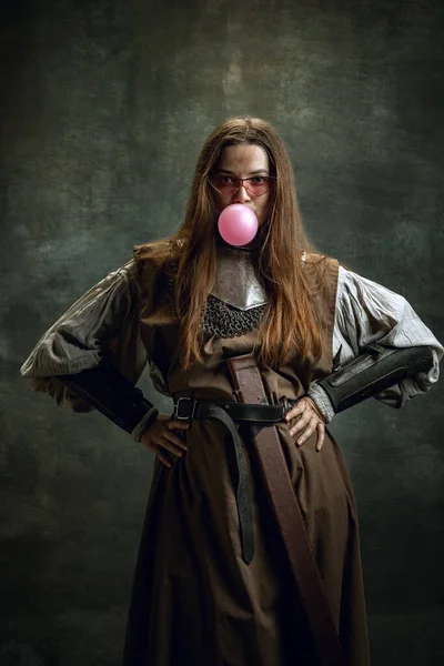 Retrato de mujer adorable, guerrera medieval o caballero con la cara sucia herida mirando a la cámara aislada sobre fondo retro oscuro. Emociones divertidas meme — Foto de Stock