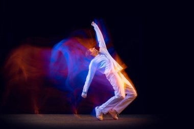 Sportif, duygusal bir adam, dansçı, hip-hop dansçısı, karanlık arka planda izole edilmiş, neon ışıklı. Gençlik kültürü, hip-hop, hareket, tarz ve moda, aksiyon.
