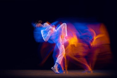 Sportif, duygusal bir adam, dansçı, hip-hop dansçısı, karanlık arka planda izole edilmiş, neon ışıklı. Gençlik kültürü, hip-hop, hareket, tarz ve moda, aksiyon.