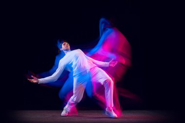 Sportif, duygusal bir adam, dansçı, hip-hop dansçısı, karanlık arka planda izole edilmiş, neon ışıklı. Gençlik kültürü, hip-hop, hareket, tarz ve moda, aksiyon.