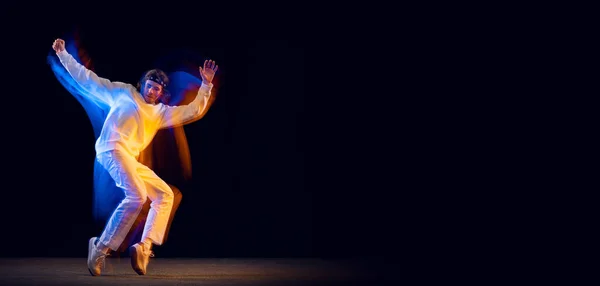 Динамический портрет танцовщика хип-хопа, танцующего на тёмном фоне в смешанном неоновом свете. Молодежная культура, хип-хоп, движение, стиль и мода, экшн. — стоковое фото