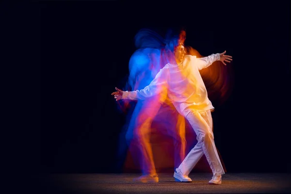 Молодежные танцы. Динамический портрет танцовщицы хип-хопа в действии, движение изолировано на тёмном фоне в смешанном неоновом свете. Молодежная культура, хип-хоп, стиль и мода — стоковое фото