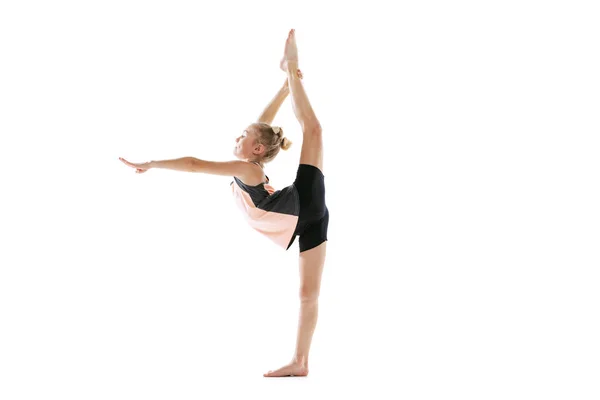 Liten flexibel flicka, rytmisk gymnastik artist isolerad på vit studio bakgrund. Nåd i rörelse, handling. Göra övningar i flexibilitet. — Stockfoto