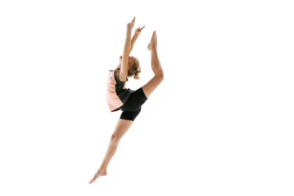 Niña flexible, artista de gimnasia rítmica saltando aislada sobre fondo blanco del estudio. Gracia en movimiento, acción. Hacer ejercicios de flexibilidad. — Foto de Stock
