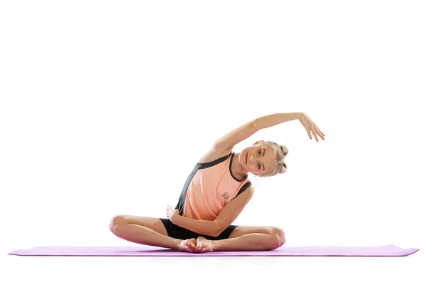 Portrait of sportive beautiful little girl, rhythmic gymnastics artist doing flexible exercises isolated on white studio background. Grace in motion, action. — Stock Photo, Image