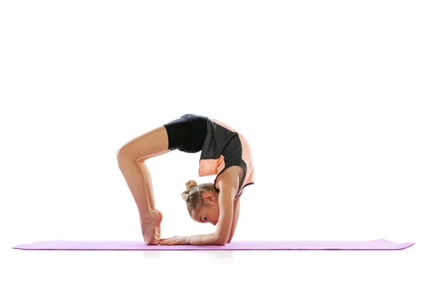 En flexibel ung flicka, rytmisk gymnastik konstnär öva isolerad på vit studio bakgrund. Nåd i rörelse, handling. Göra övningar i flexibilitet. — Stockfoto