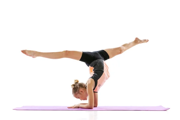 Little flexible girl, rhythmic gymnastics artist isolated on white studio background. Grace in motion, action. Doing exercises in flexibility. — Stock Photo, Image