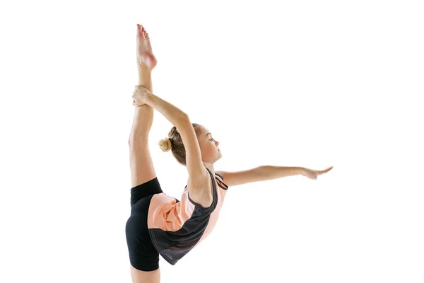 Pequena menina flexível, artista de ginástica rítmica isolada no fundo do estúdio branco. Graça em movimento, acção. Fazendo exercícios em flexibilidade. — Fotografia de Stock