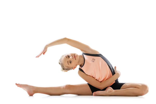 Portret van sportief mooi klein meisje, ritmische gymnastiek kunstenaar doen flexibele oefeningen geïsoleerd op witte studio achtergrond. Genade in beweging, actie. — Stockfoto