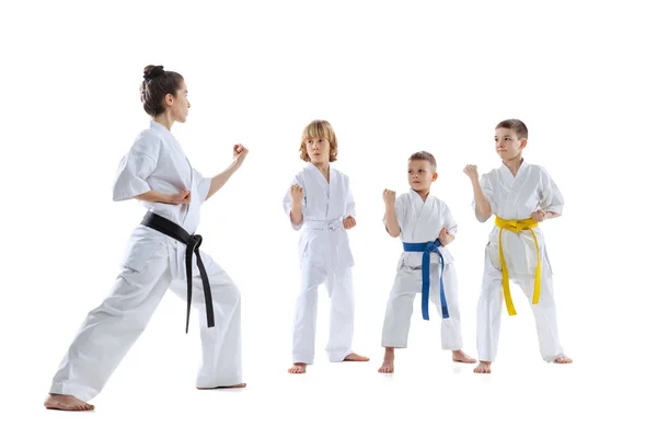 Grupo de niños, niños, atletas taekwondo usando doboks entrenamiento con maestro aislado sobre fondo blanco. Concepto de deporte, artes marciales — Foto de Stock
