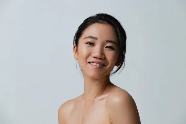 Porträtt av vackra glada asiatiska flicka med naturlig makeup poserar isolerad över grå studio bakgrund — Stockfoto