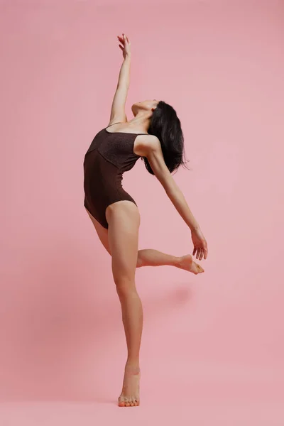 Retrato completo de jovem mulher macia em bodysuit dançando isolado sobre fundo de estúdio rosa — Fotografia de Stock