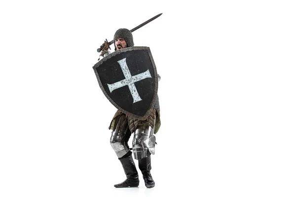 Портрет жорстокого серйозного чоловіка, середньовічного воїна або лицаря в захисному покритті з мечем, який готується атакувати ізольовано на білому студійному фоні — стокове фото