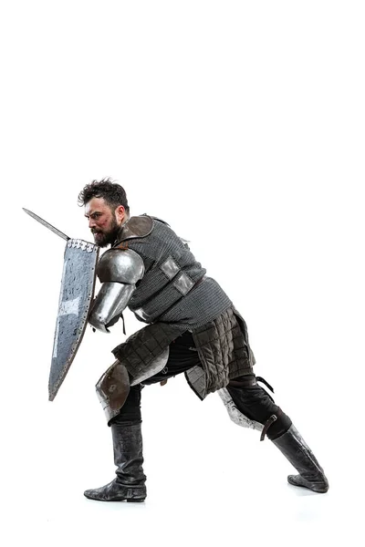 Retrato de valiente guerrero medieval, caballero con armadura especial protegiéndose con escudo y espada aislado sobre fondo blanco del estudio —  Fotos de Stock