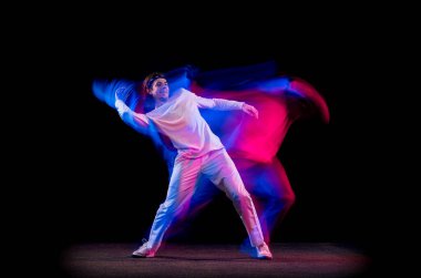 Özgürlük için. Erkek hip-hop dansçısının dinamik portresi. Karmaşık neon ışıkta koyu arka planda izole edilmiş. Gençlik kültürü, hip-hop, hareket, tarz ve moda, aksiyon.