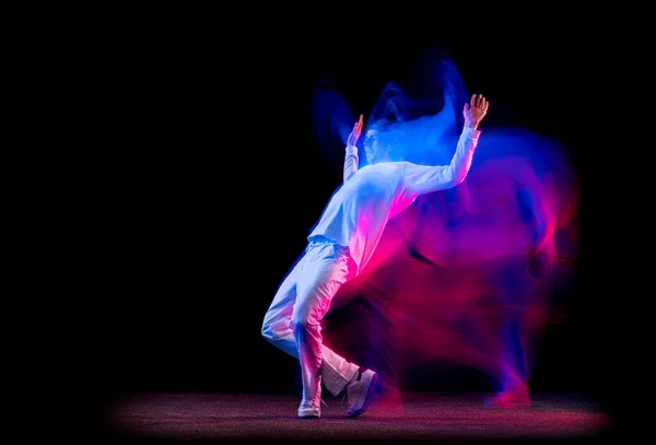 Retrato dinâmico de dançarino de hip-hop masculino dançando isolado em fundo escuro em luz de néon mista. Cultura juvenil, hip-hop, movimento, estilo e moda, ação. — Fotografia de Stock