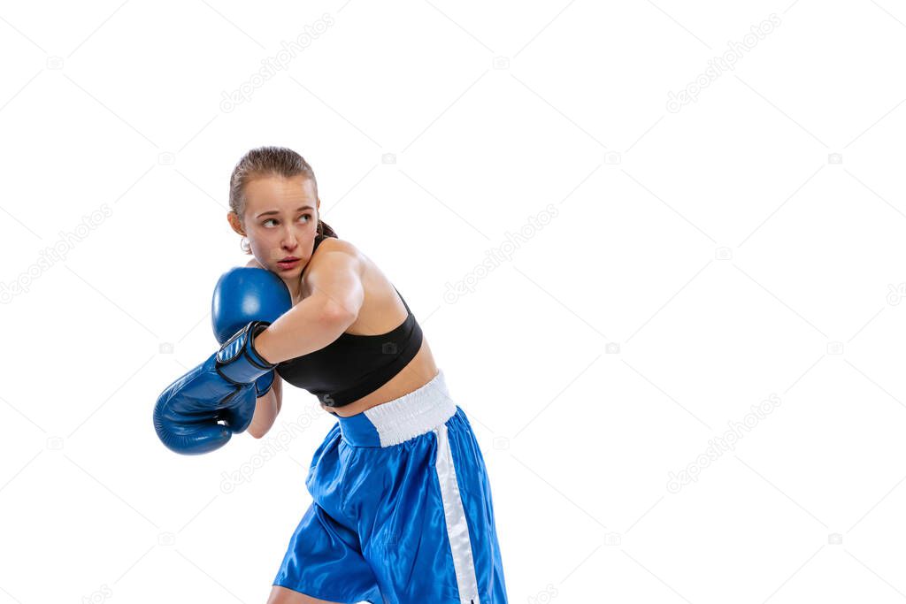 In action, motion. Young girl, professional boxer practicing in boxing gloves isolated on white studio background. Concept of sport, studying, competition