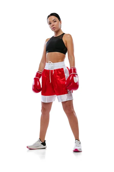 Ritratto di giovane bella ragazza, pugile professionista in pantaloncini da boxe e guanti in posa isolata su sfondo bianco da studio. Concetto di sport, studio, competizione — Foto Stock