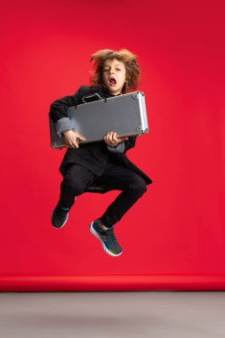 Liitle 'ın tam boy portresi, şık bir kuaför görüntüsü, kırmızı arka planda berber atlayışı. Meslek kavramı, modern uzmanlar, çocukluk.